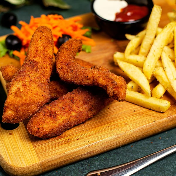 Crispy chicken tenders and golden french fries served with shredded carrots, olives, and dipping sauces.